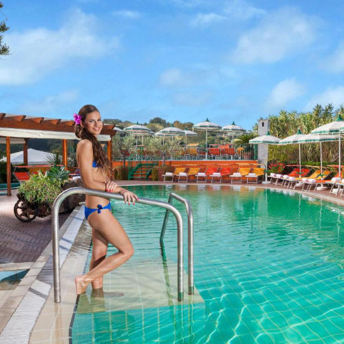 Piscine extérieure de la Villa Flavio entourée de parasols et de chaises longues.