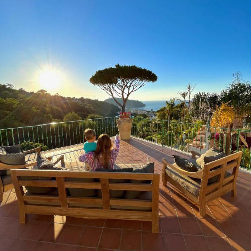Terrasse panoramique de la Villa Flavio offrant une vue spectaculaire sur la mer au coucher du soleil.