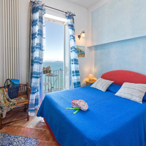 Chambre lumineuse aux accents bleus avec balcon et vue sur la mer à la Villa Lieta Ischia.