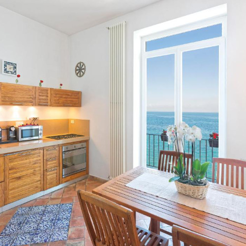 Cuisine et coin repas avec une large ouverture sur les eaux turquoise à la Villa Lieta Ischia.