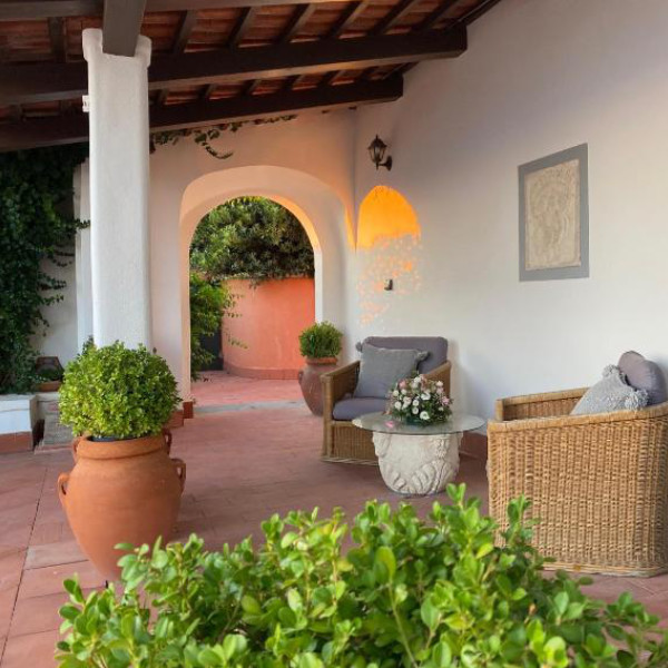 Terrasse couverte aménagée avec des fauteuils en osier et des poteries traditionnelles.