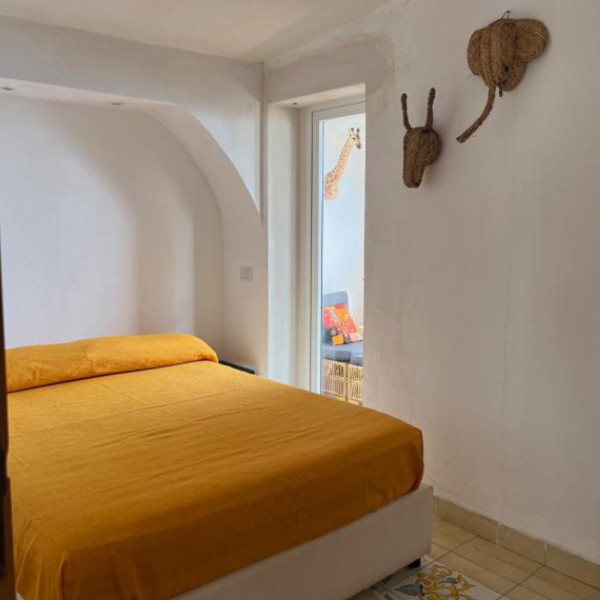 Chambre accueillante avec un lit jaune et des décorations murales en paille en forme d'animaux.