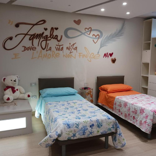 Chambre accueillante de la Villa Nadia avec deux lits simples et un grand ours en peluche.