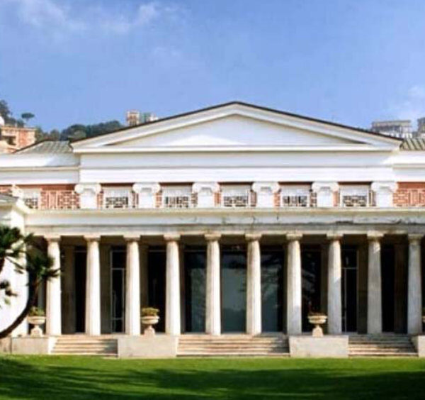 Façade néoclassique de la Villa Pignatelli à Naples avec colonnade monumentale et jardin verdoyant.