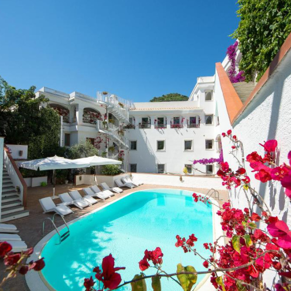 Piscine extérieure de l'hôtel Villa Romana entourée de transats et de bougainvilliers.