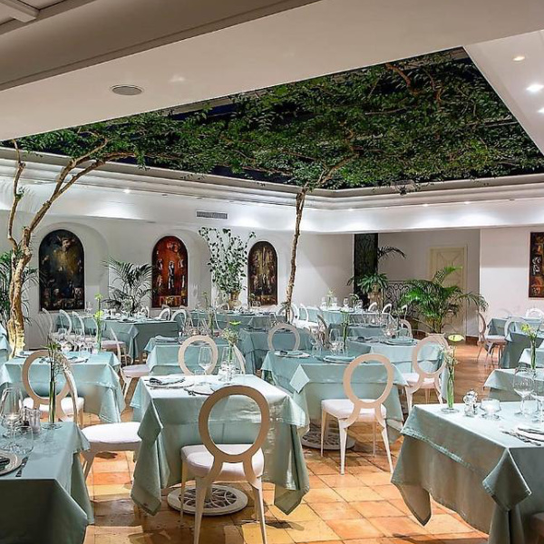 Salle de restaurant raffinée de l'hôtel Villa Romana avec une décoration végétale atypique.