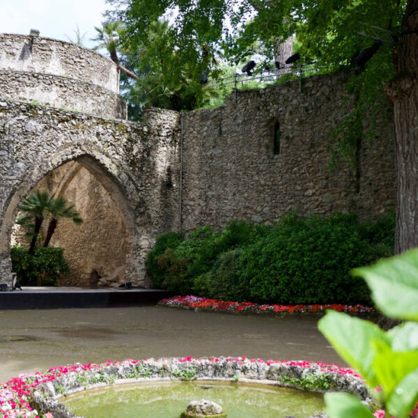 Villa Rufolo à Ravello avec jardin fleuri, arc en pierre et architecture médiévale sur la Côte Amalfitaine.