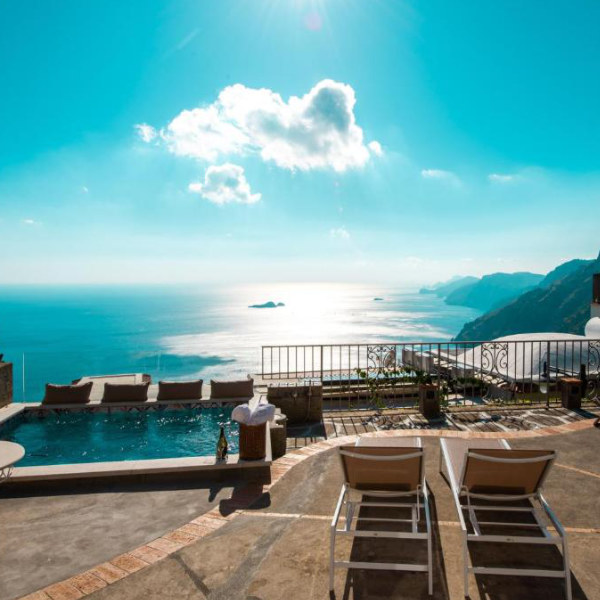 Piscine panoramique de Ville Olimpo à Positano avec transats et vue sur la côte.