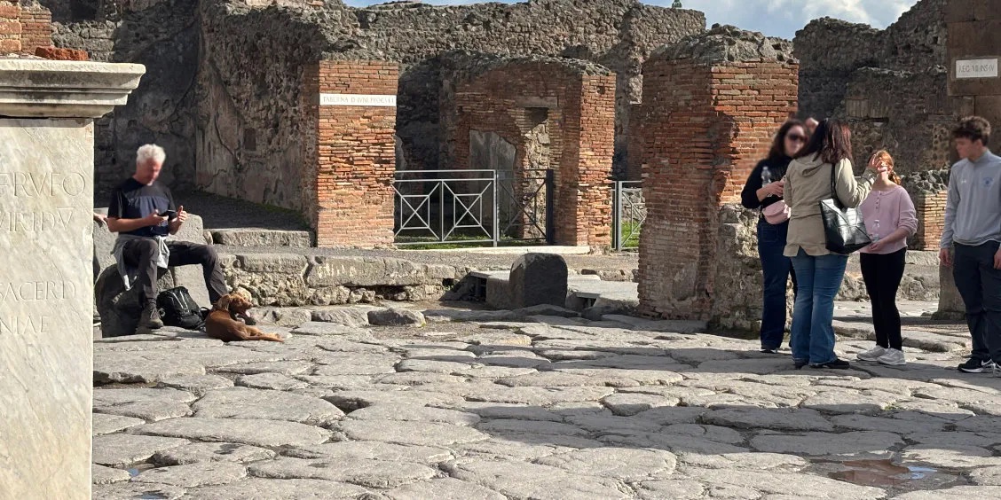 Visiteurs dans les ruines de Pompéi avec vestiges romains et rue pavée.