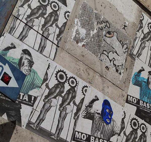 Mur couvert d'affiches de street art et panneau senso unico dans une ruelle du centre historique de Naples.