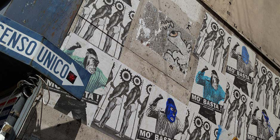 Mur couvert d'affiches de street art et panneau senso unico dans une ruelle du centre historique de Naples.