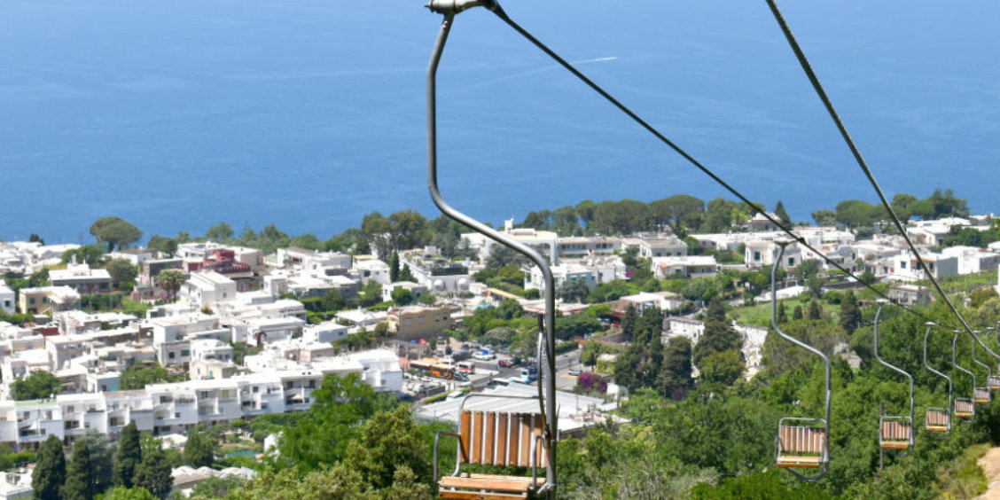 Chaises du télésiège du Mont Solaro survolant les maisons blanches d'Anacapri.
