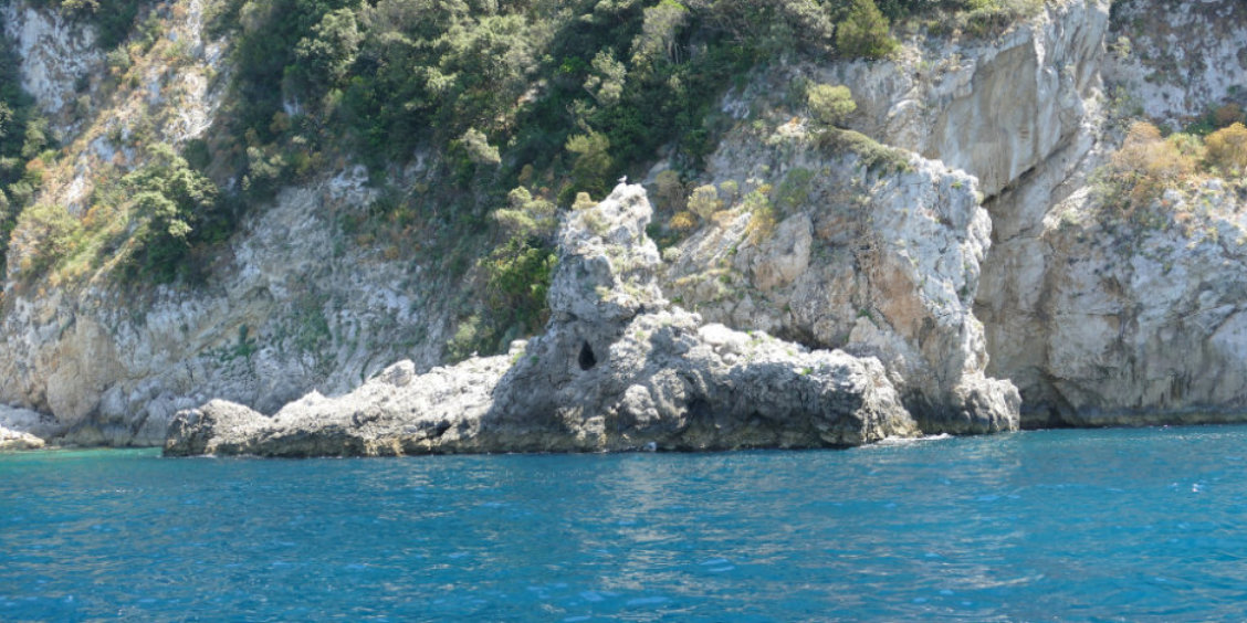 Formation rocheuse escarpée au bord des eaux bleues de Capri avec une petite cavité naturelle.