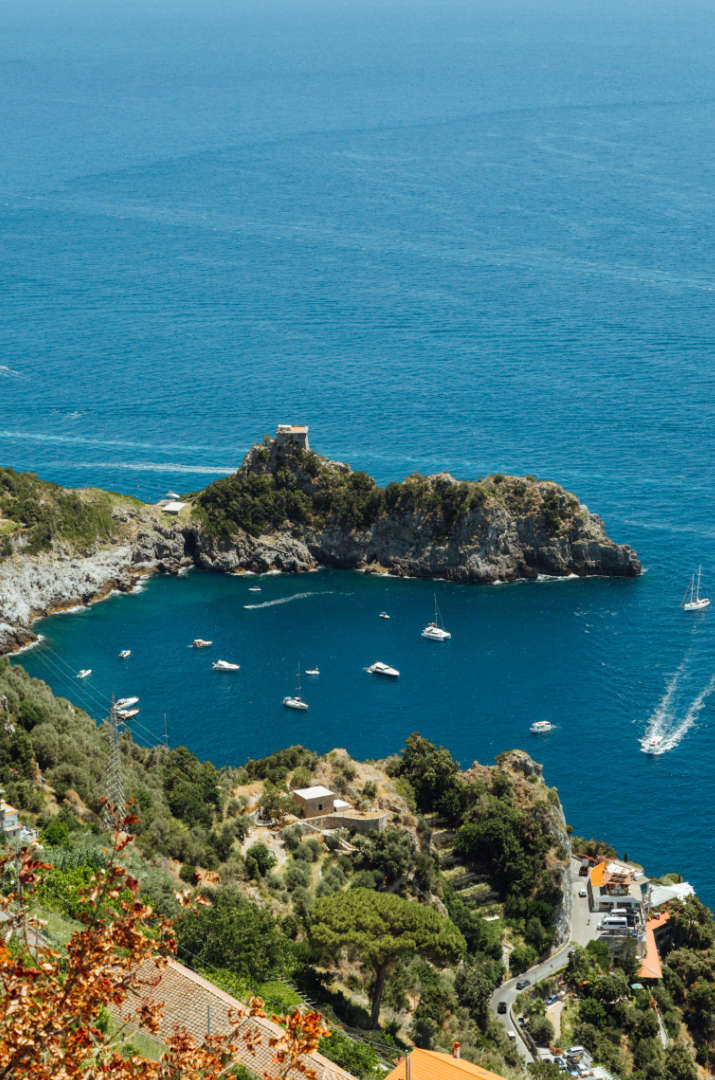 Crique de la Côte Amalfitaine avec eaux turquoise et bateaux au pied des falaises.