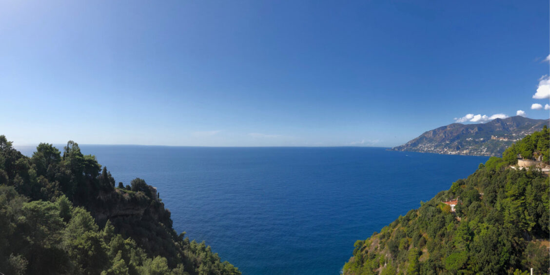 Vue panoramique sur la Côte Amalfitaine avec falaises verdoyantes et horizon sur la mer Méditerranée.