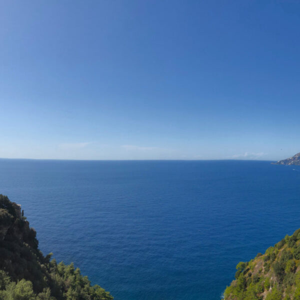 Vue panoramique sur la Côte Amalfitaine avec falaises verdoyantes et horizon sur la mer Méditerranée.