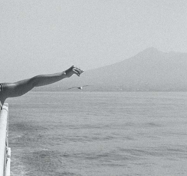Enfant regardant le Vésuve depuis la mer à Naples, image symbolique d’un voyage en famille à Naples.