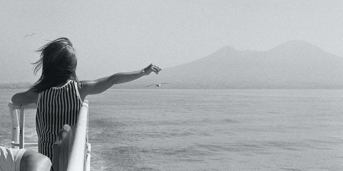 Enfant regardant le Vésuve depuis la mer à Naples, image symbolique d’un voyage en famille à Naples.