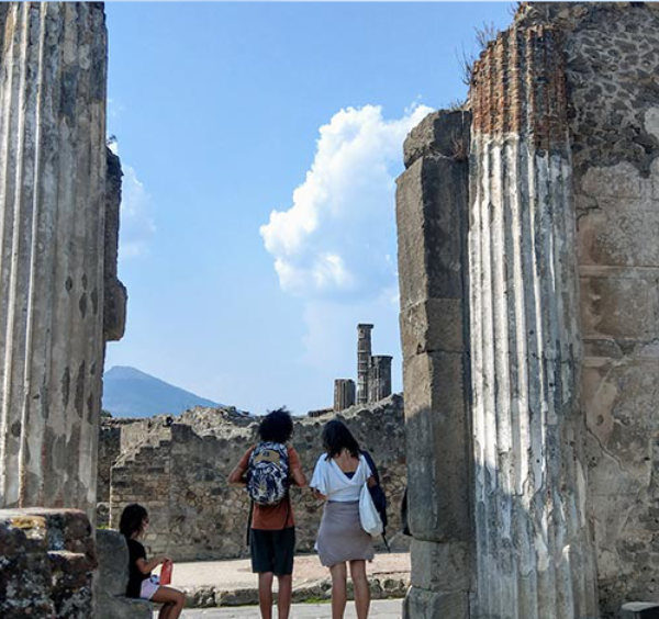 Touristes contemplant les ruines de Pompéi et le Vésuve à l'horizon.