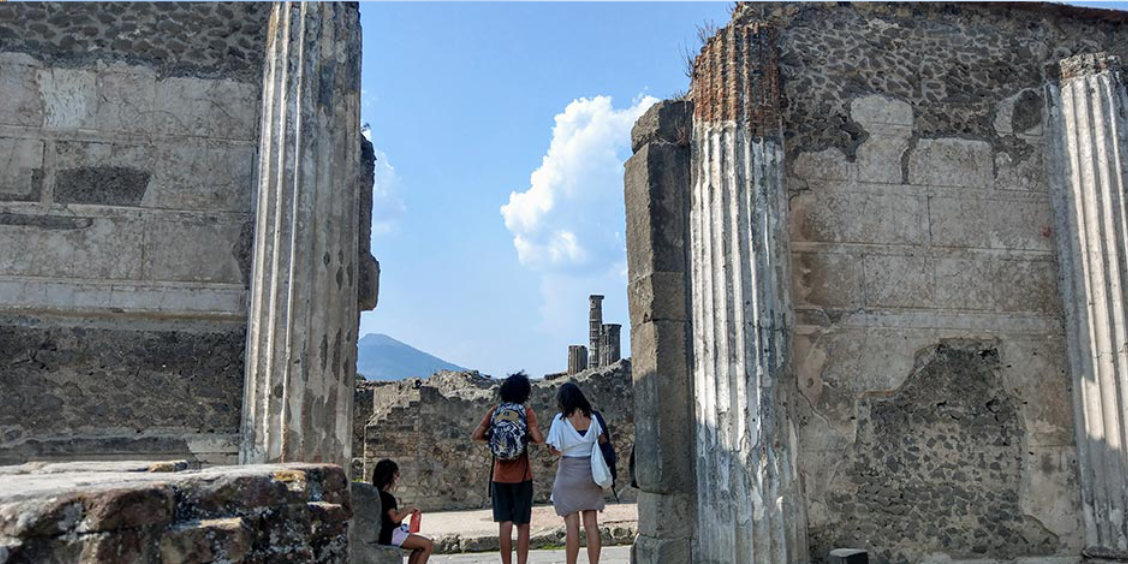 Touristes contemplant les ruines de Pompéi et le Vésuve à l'horizon.