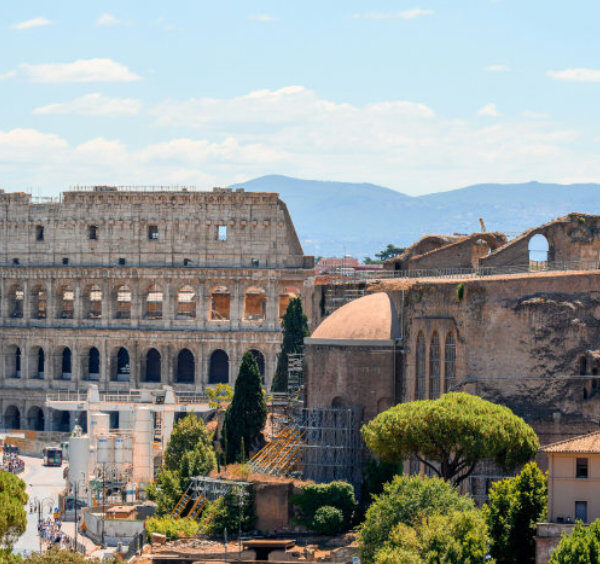 Panorama sur les vestiges antiques de Rome avec le Colisée et les pins parasols typiques bordant le Forum Romain.