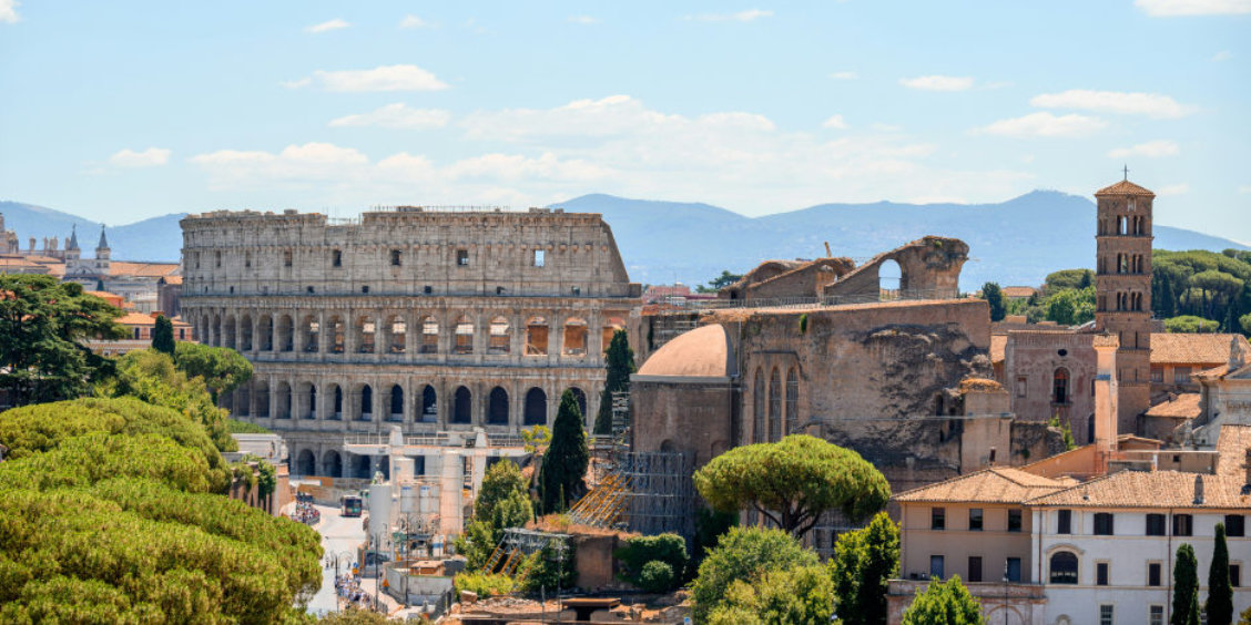 Panorama sur les vestiges antiques de Rome avec le Colisée et les pins parasols typiques bordant le Forum Romain.