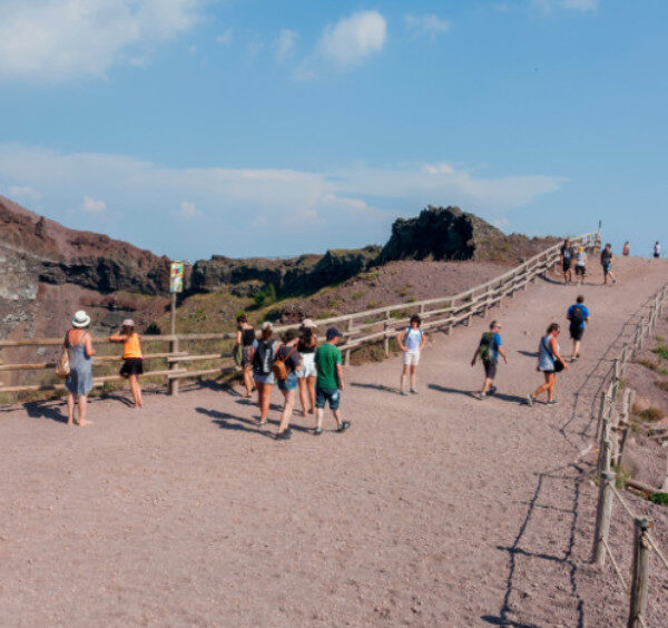Visiteurs sur le sentier de randonnée du cratère du Vésuve en Campanie, entourés de paysages volcaniques secs.
