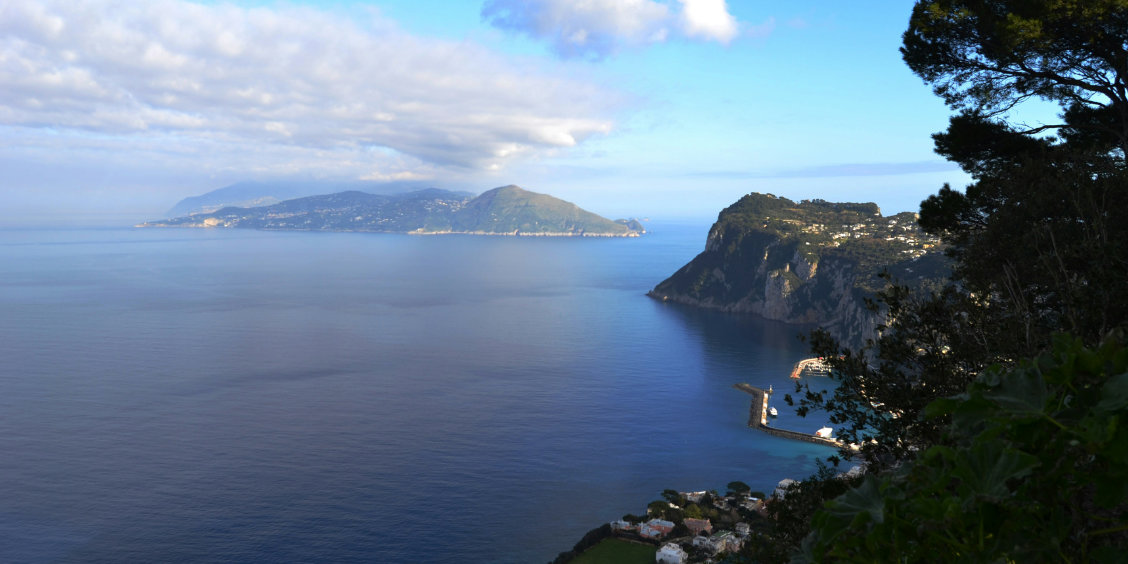 Vue imprenable depuis les hauteurs de Capri sur le port de Marina Grande et la silhouette de la côte au loin.
